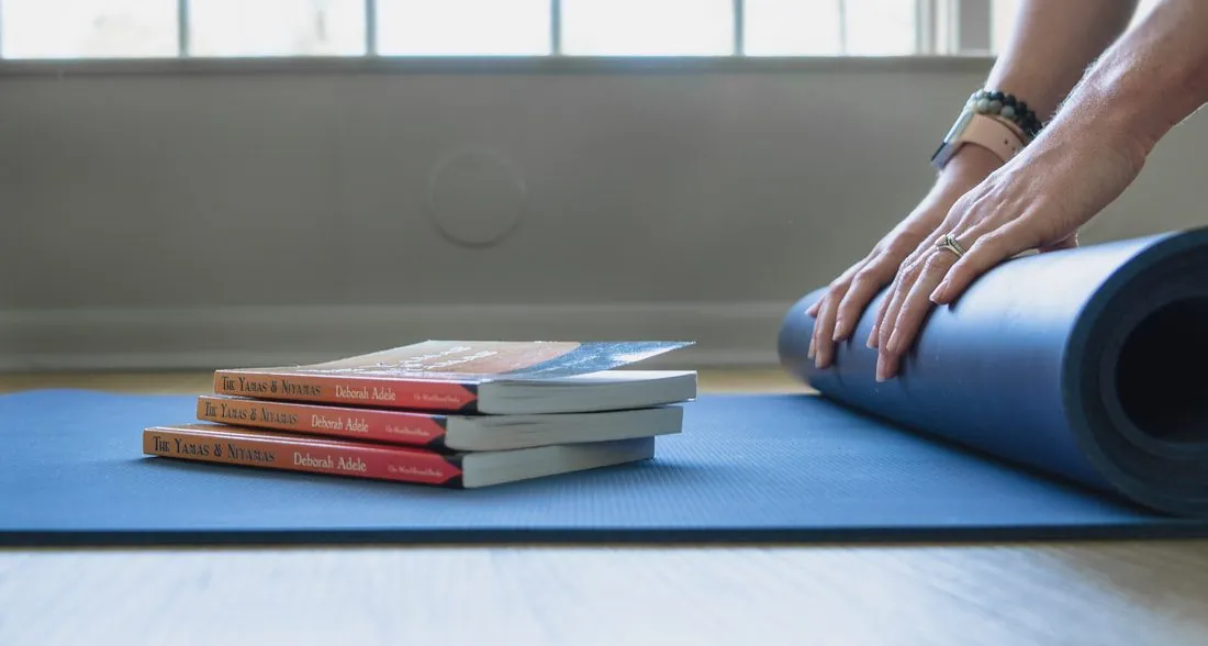 Books stacked beside a rolled yoga mat